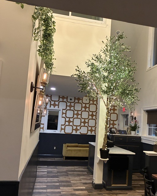 La Familia Wrentham entryway with an olive tree, patterned wall and host stand
