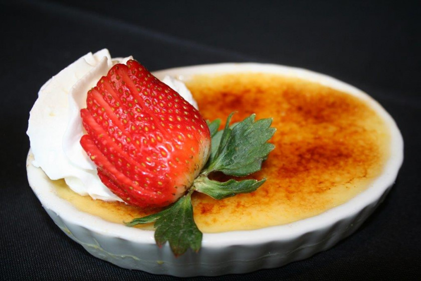 Creme brulee with a sliced strawberry and whipped cream
