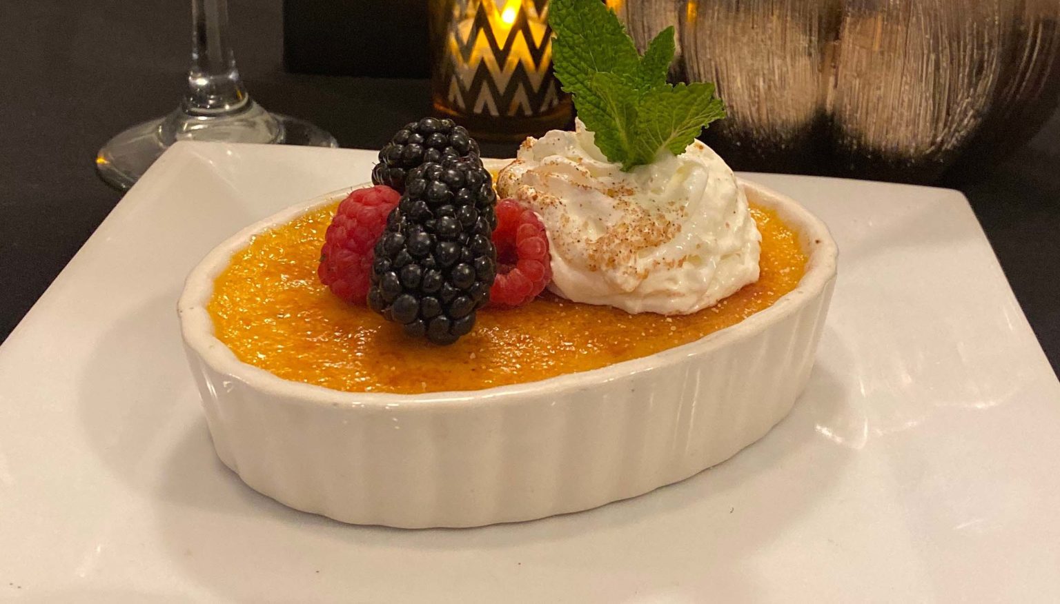 Creme brulee with fresh berries, whipped cream and mint